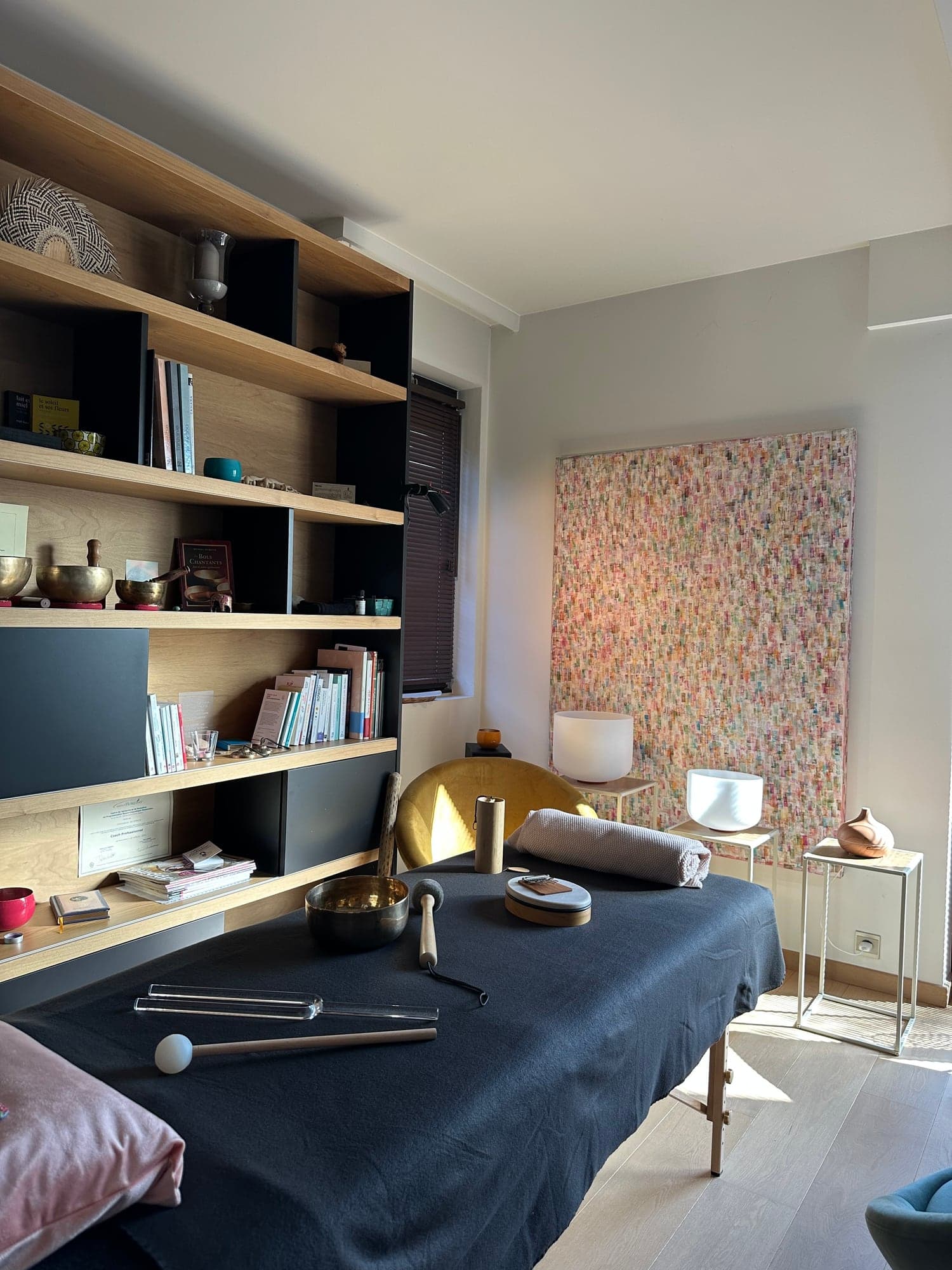 L’espace de soin baigné de lumière : table de massage, bols tibétains, diapasons et bols de cristal